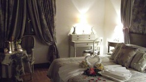Ein Schlafzimmer mit einem Bett, einem Nachttisch, einer Kommode, einem Sessel und einem Tisch mit einer Lampe.