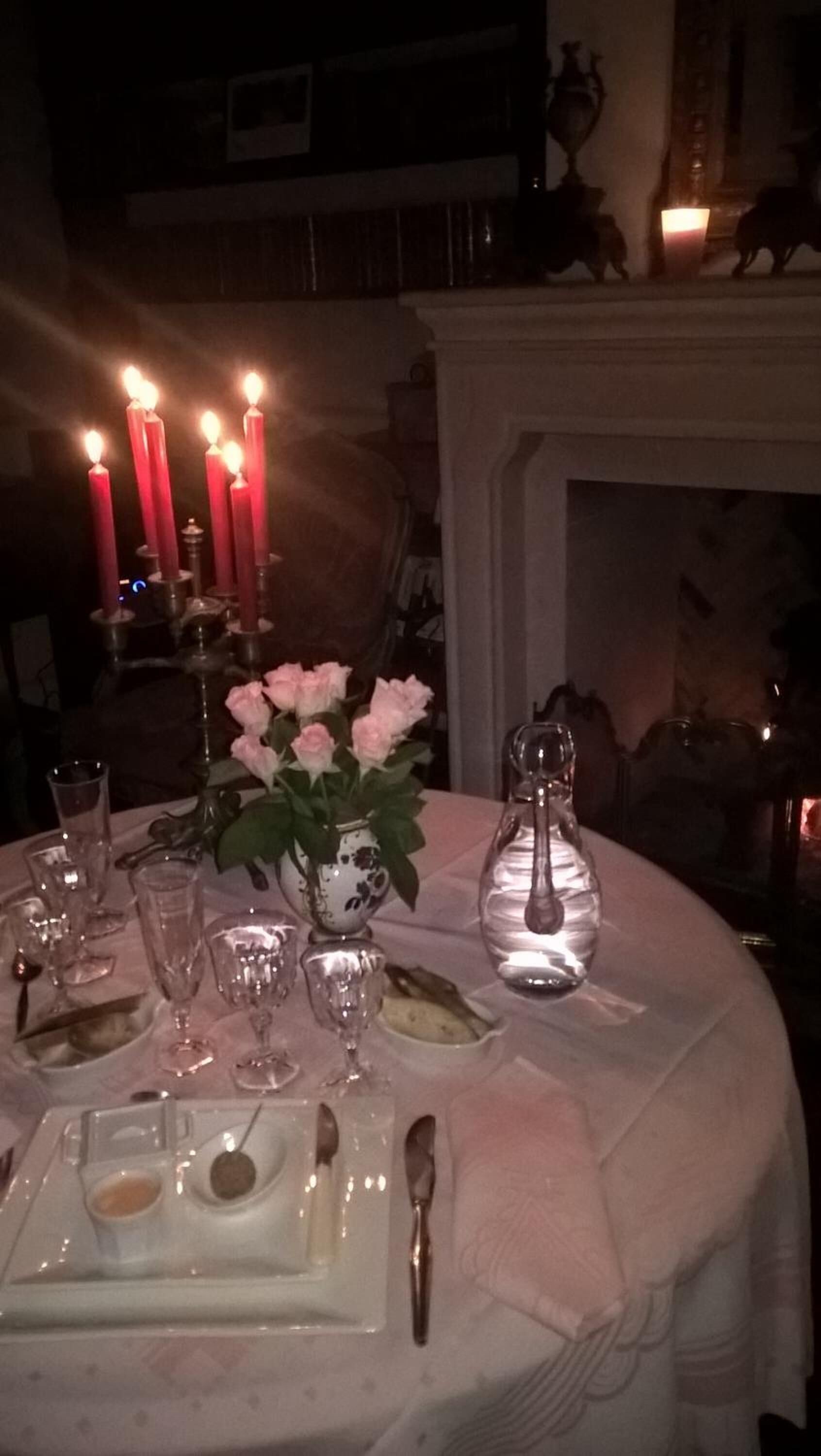 Una mesa dispuesta para comer, con velas, un florero y salero y pimentero.