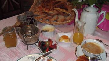 Una mesa de desayuno con pan, bollería, fruta, miel, mermelada y café.