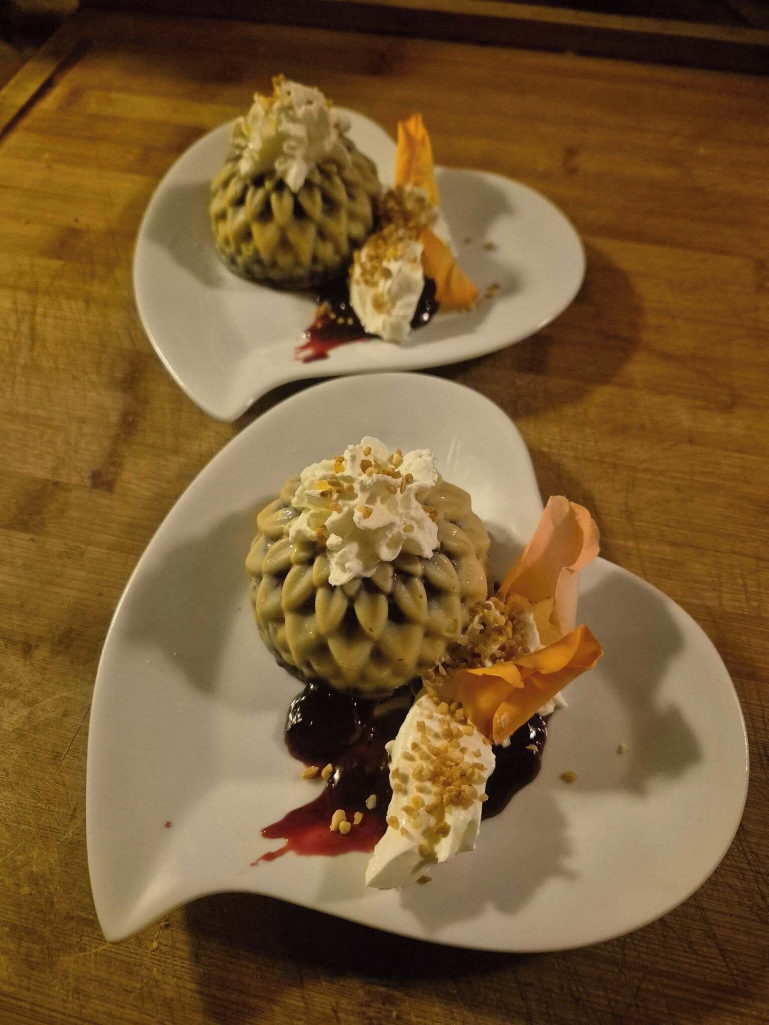 Two white plates with desserts on a wooden table.