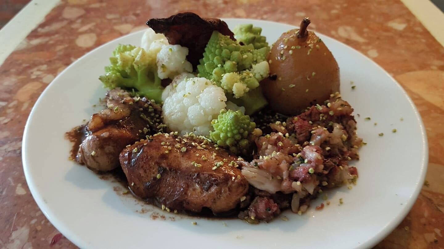 Un piatto con pollo alla griglia, broccoli, cavolfiore e una pera.