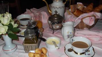 Une table dressée avec du thé, du café, des pâtisseries et un vase de fleurs.
