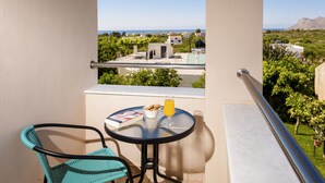 A balcony with a table, a chair, a book, a glass of juice, and a view of the landscape. - Dream villa luxury with private  heated pool and BBQ (chania)