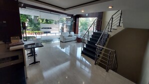 A spacious living area with a sofa, a coffee table, and a staircase with a metal railing. - Broadway Inn (Jaipur)