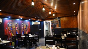 A restaurant with wooden ceiling and walls, tables set with plates, cutlery, and glasses. - Broadway Inn (Jaipur)