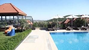 A poolside area with lounge chairs, a swing chair, and umbrellas. - Myosotis Boutique Otel (Foça)