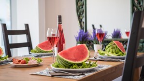 Uma mesa de jantar com pratos de comida, uma garrafa de vinho e copos de vinho tinto.