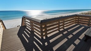 Eine Holzterrasse mit Blick auf einen Strand und eine klare Meeransicht.