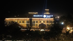 Un edificio grande con un letrero que dice 'SHAMROCK JARDIN HOTELS' de noche.