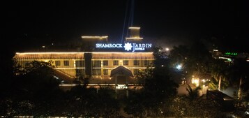 Un edificio grande con un letrero que dice 'SHAMROCK JARDIN HOTELS' de noche.