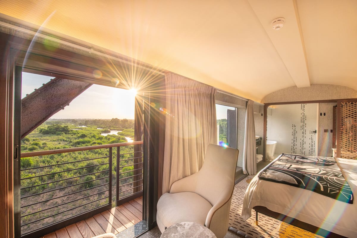 Une chambre avec un lit, une chaise et une vue sur un paysage.