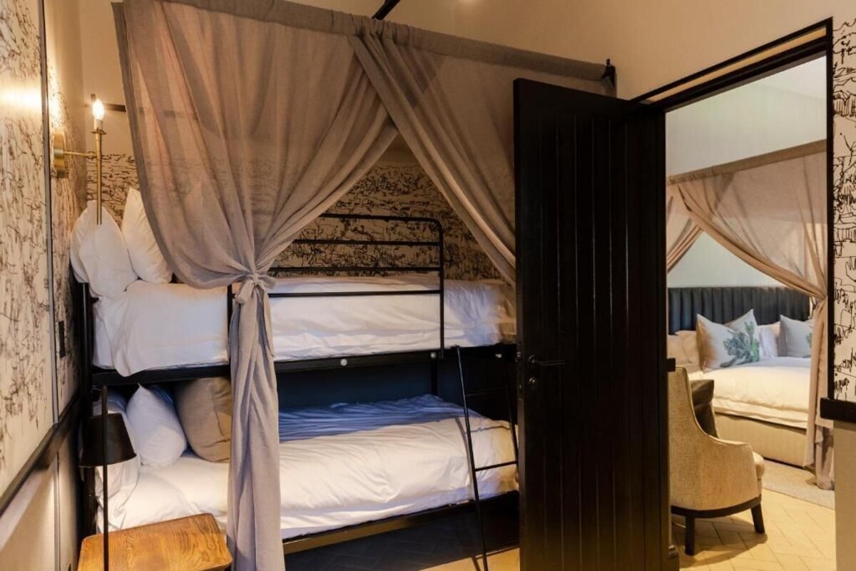 Een kamer met een stapelbed, een stoel en een bed met hemel.