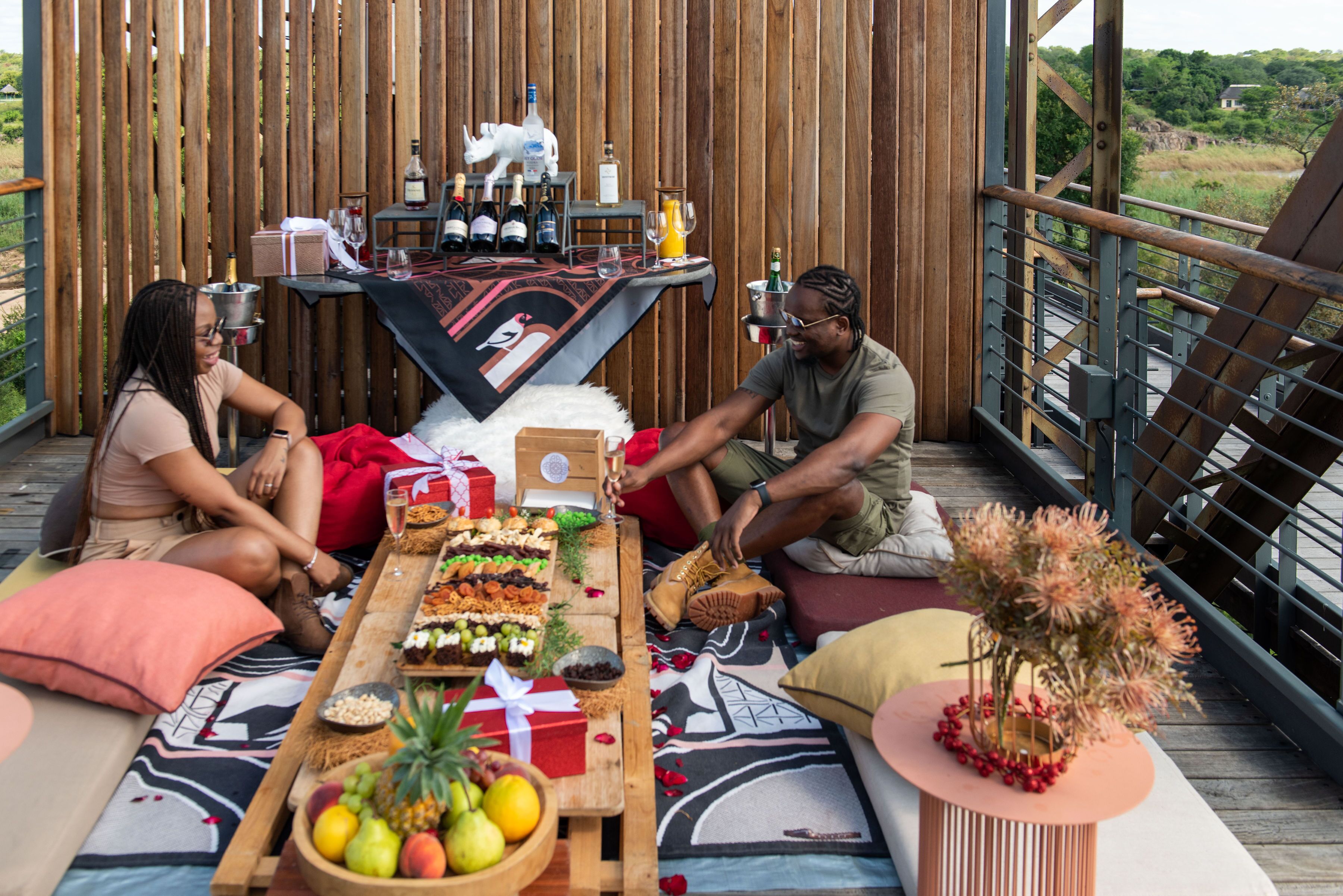 Une terrasse en bois avec une table dressée pour un repas, entourée d’une clôture en bois.