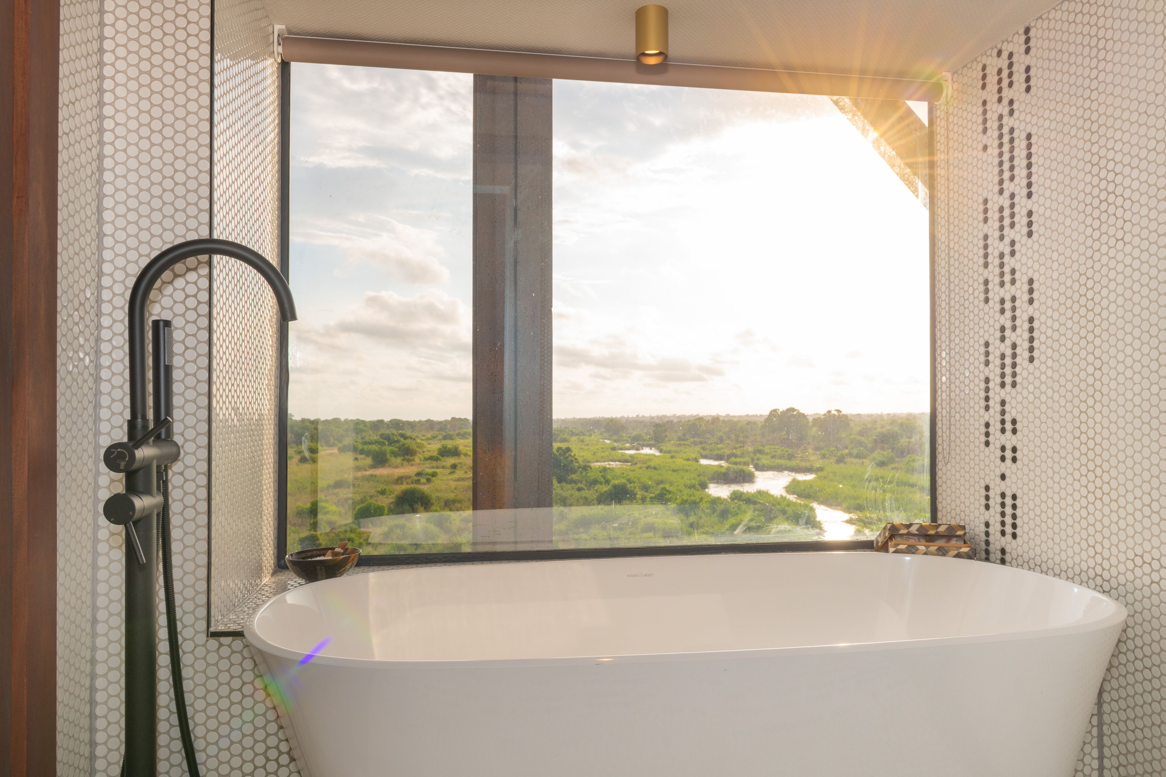 A bathroom with a large bathtub, a shower, and a view of a river and greenery.