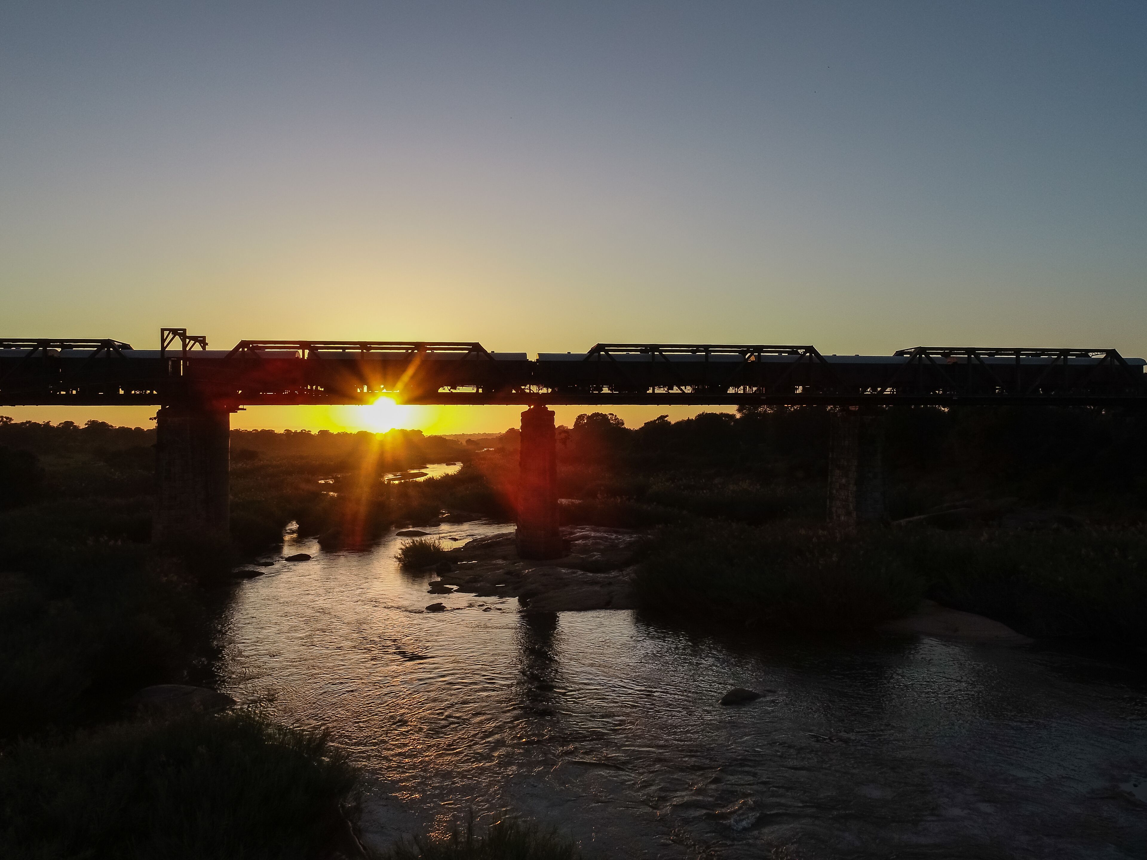 Un puente sobre un río al atardecer, con un tren cruzando.