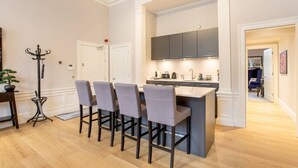 Une cuisine moderne dotée d’un îlot central, de tabourets de bar et d’un coin repas avec une table et des chaises.