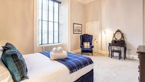 Une chambre à coucher avec un grand lit, une fenêtre, une chaise, une commode et un miroir.
