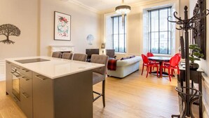 Une cuisine moderne avec un îlot central, un coin repas avec des chaises rouges et un espace salon confortable avec un canapé.