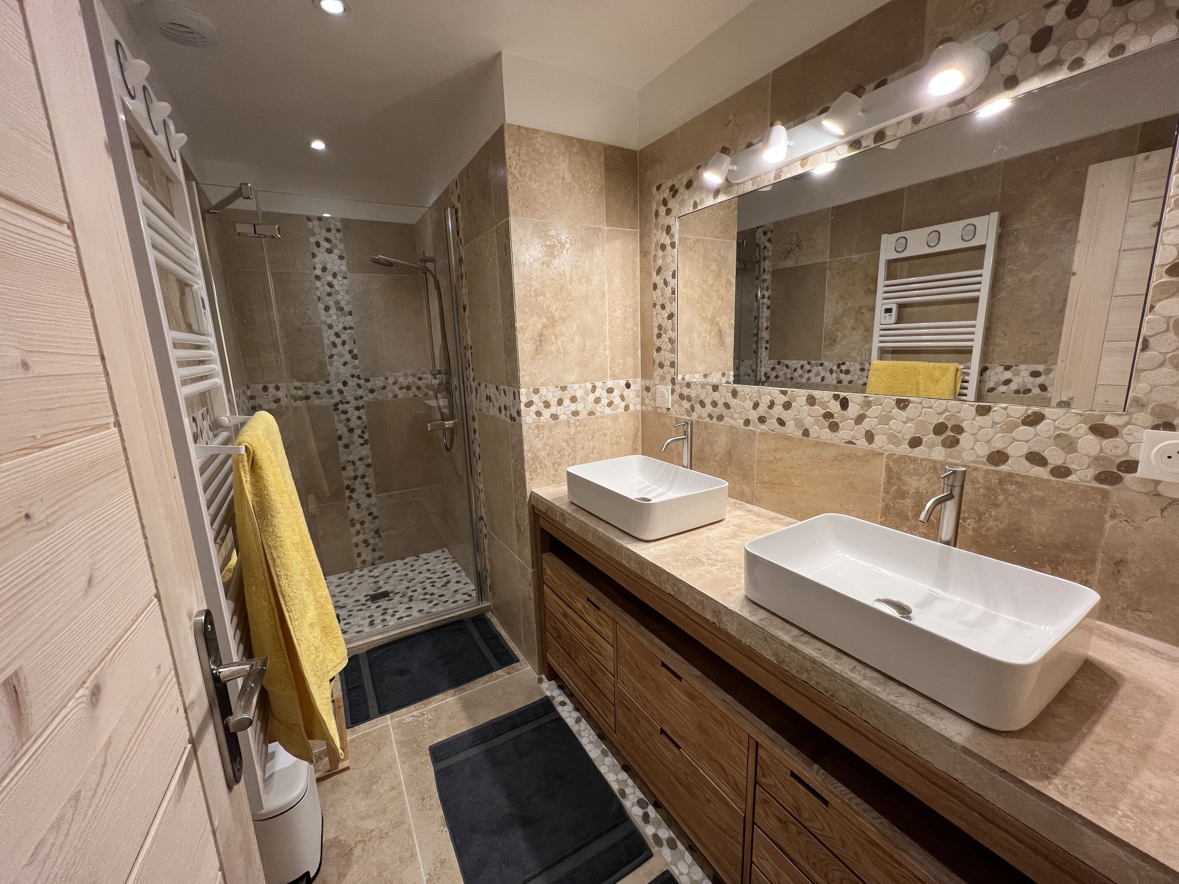 A modern bathroom with a glass-enclosed shower, two sinks, and a large mirror.