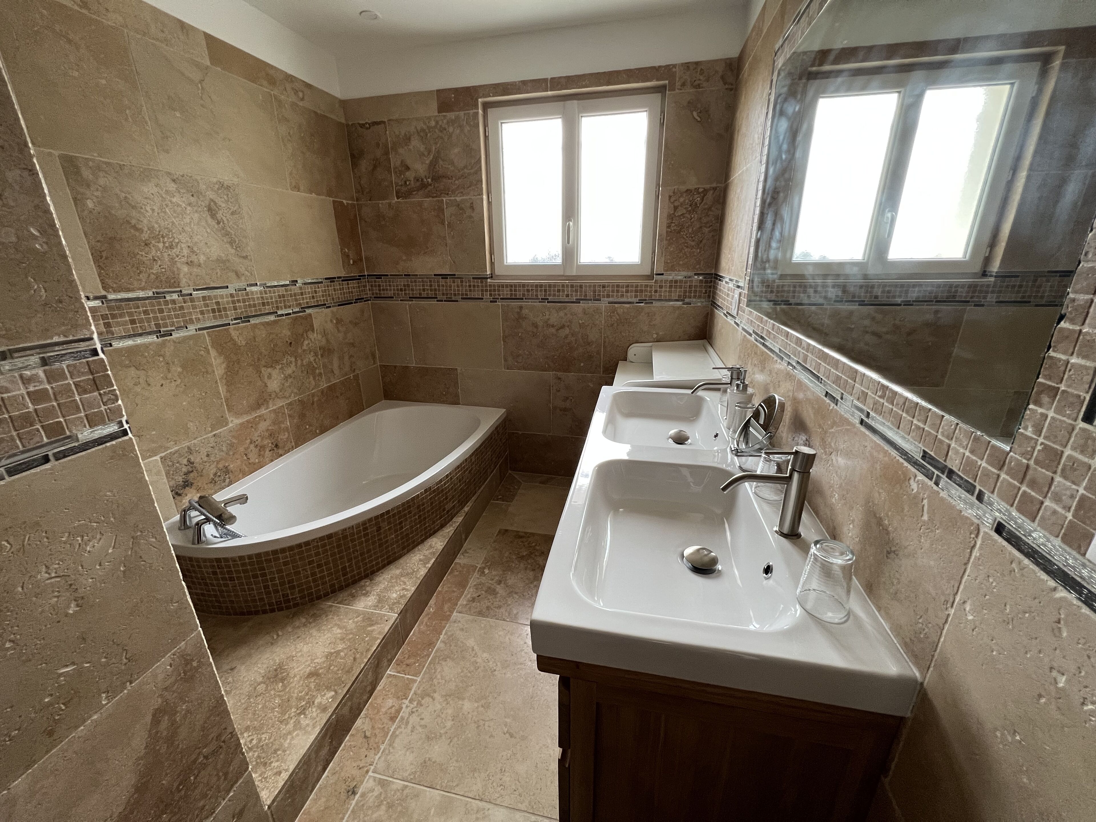 Ein Badezimmer mit einer Badewanne, zwei Waschbecken und einem großen Spiegel.