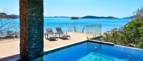 An infinity pool with a clear view of the sea and distant islands.