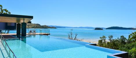 A modern infinity pool with a clear view of the sea and distant islands.