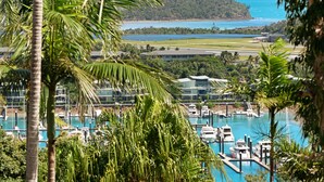 A marina with boats docked, surrounded by lush greenery and a clear view of the ocean. - Oasis 17 (Whitsundays)