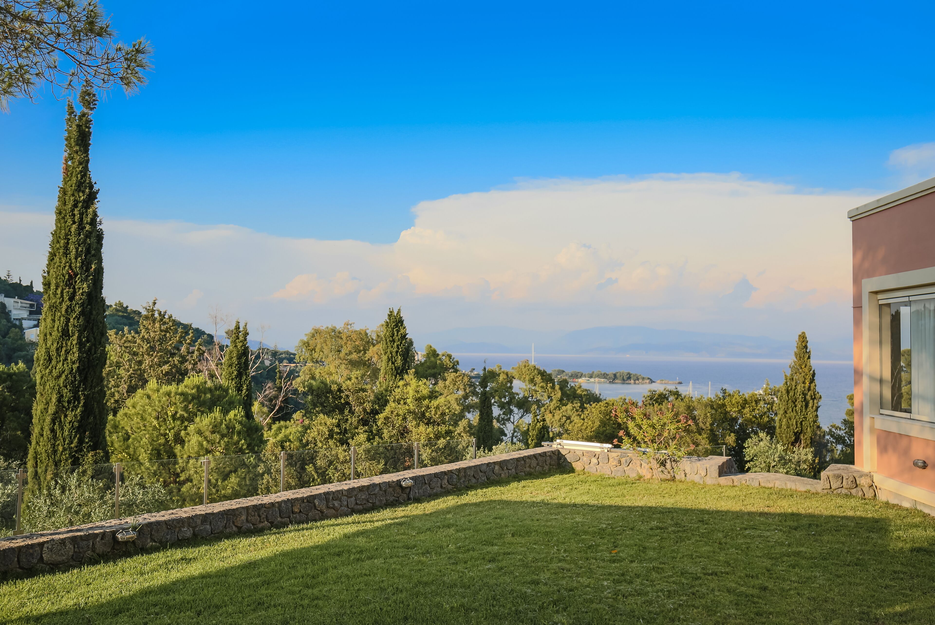 Un'area erbosa con un muro in pietra e vista su un corso d'acqua e terre lontane.