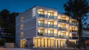 A multi-story hotel with balconies, large windows, and a well-lit entrance. - Villa Sv Kriz (Trogir)