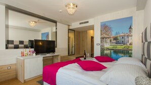 A modern hotel room with a large bed, a TV, a desk, and a painting of a house and pond. - Villa Sv Kriz (Trogir)
