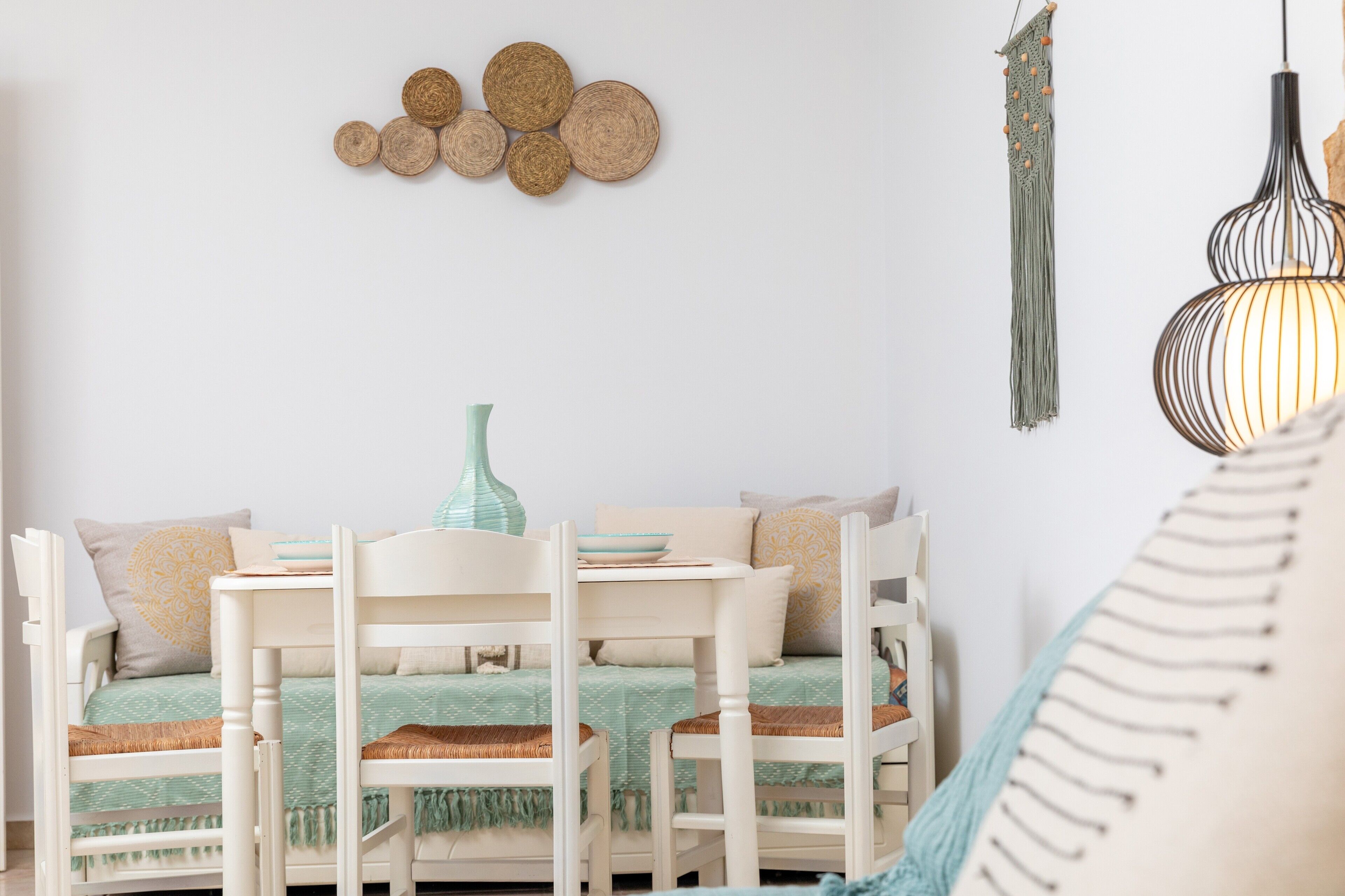 A cozy room with a white sofa, a small table, and a hanging light fixture.
