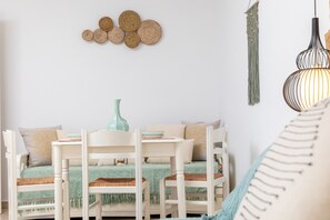 Ein gemütliches Zimmer mit einem weißen Sofa, einem kleinen Tisch und einer Hängelampe.
