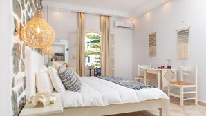 Camera da letto con un letto, comodini, lampadario, finestra con tende, condizionatore d'aria a parete e vista esterna.