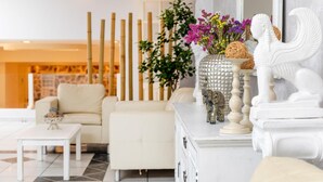 Un soggiorno moderno con un divano bianco, un tavolino, vasi decorativi e uno specchio.