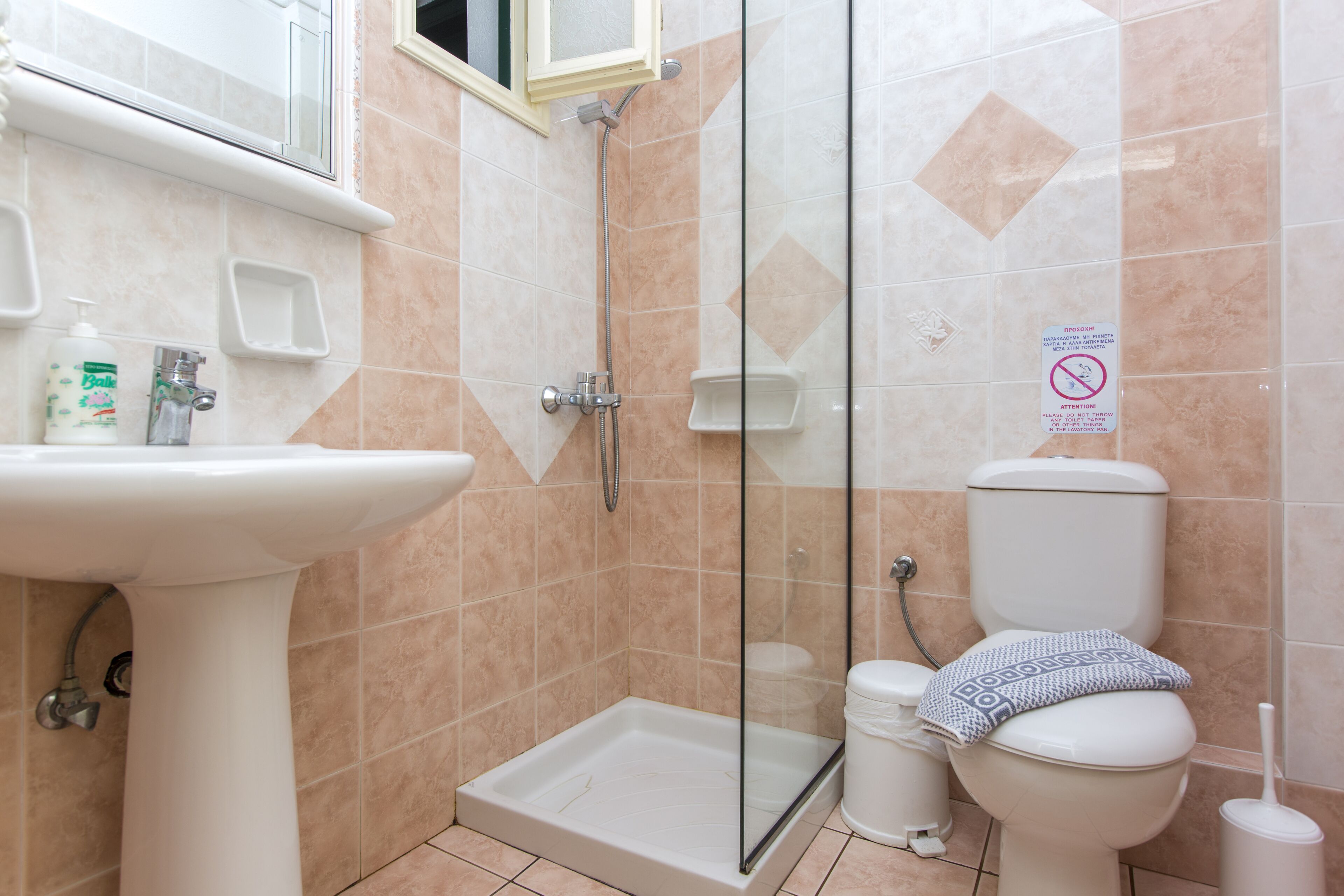 A bathroom with a shower, toilet, sink, and a glass-enclosed shower area.