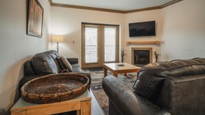 A living room with a sofa, a coffee table, a fireplace, and a television mounted on the wall. - Unit 2307 - FREE Attraction Ticket with EACH night Stay Including Dollywood (Pigeon Forge)