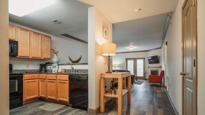 A modern kitchen with wooden cabinets, a dishwasher, and a dining area with a table and chairs. - Unit 2307 - FREE Attraction Ticket with EACH night Stay Including Dollywood (Pigeon Forge)
