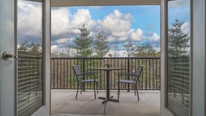 A balcony with a table and chairs, a view of trees and sky, and a wooden fence. - Unit 2307 - FREE Attraction Ticket with EACH night Stay Including Dollywood (Pigeon Forge)