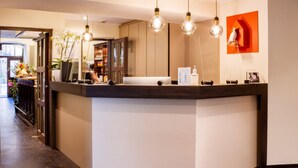 A reception area with a counter, three pendant lights, and a wall-mounted bird sculpture. - Hotel & Tafernwirtschaft zum Fischer (Dachau)
