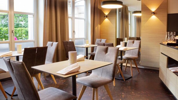 A modern restaurant with leather chairs, wooden tables, and pendant lighting. - Hotel & Tafernwirtschaft zum Fischer (Dachau)