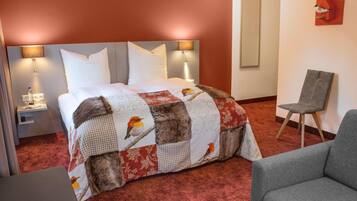 Ein Hotelzimmer mit einem großen Bett, einem Sessel und einem Nachttisch mit Lampe.