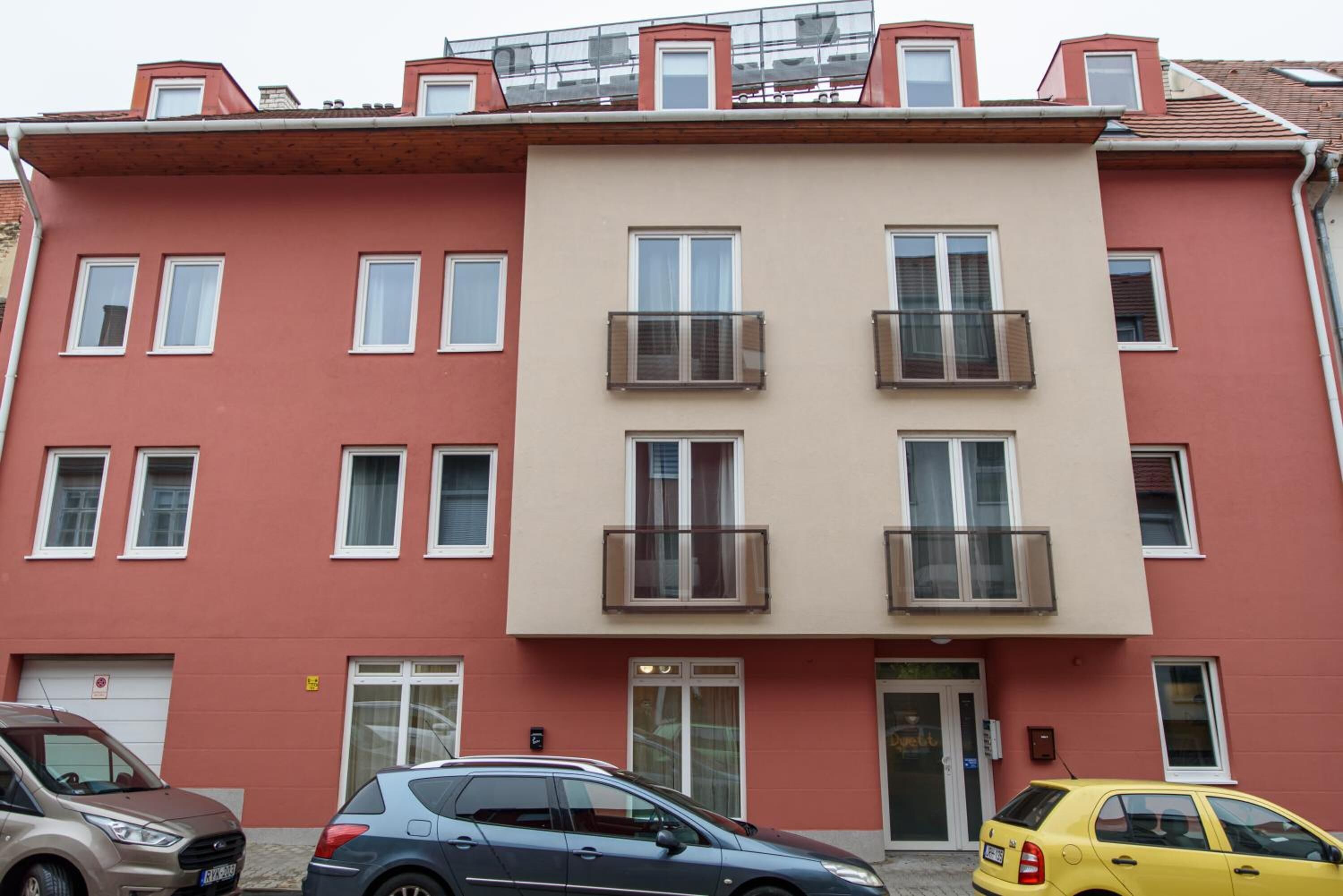 A multi-story residential building with balconies, a garage, and a door with a sign.