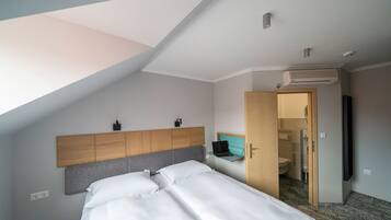 Een hotelkamer met een bed, een bureau, een kledingkast en een open deur naar een badkamer.