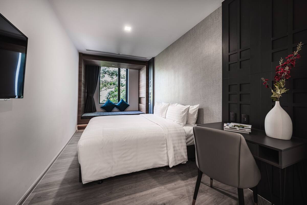Une chambre d’hôtel moderne avec un grand lit, un bureau et un téléviseur fixé au mur.