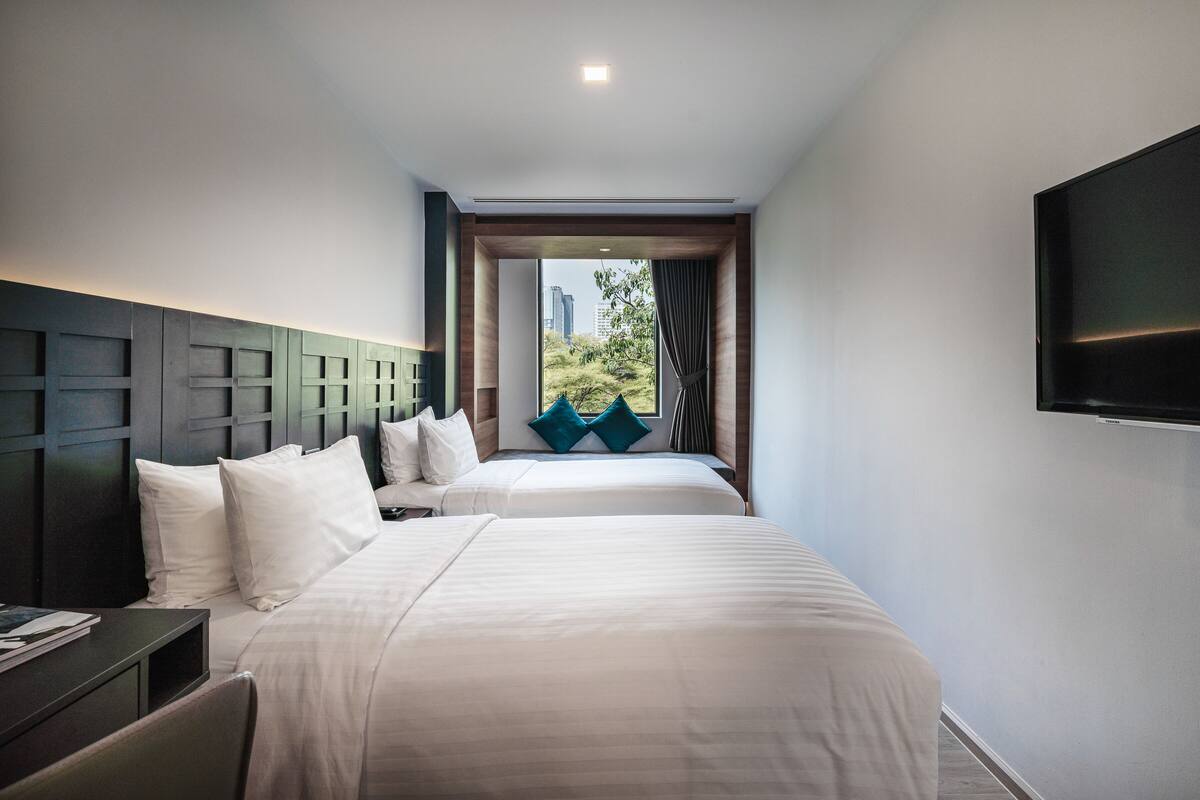 Une chambre d’hôtel avec deux lits, un téléviseur à écran plat et une fenêtre donnant sur la ville.