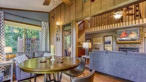 Una sala de estar acogedora con una mesa redonda de madera, un sofá gris y una chimenea.