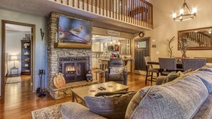 Una sala de estar acogedora con chimenea de piedra, un sofá cómodo y un comedor al fondo.