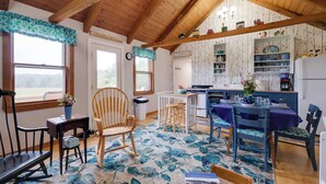 A cozy kitchen with wooden beams, a dining table set for four, and a rustic decor. - Historic Cottage on Horse Farm: FirePit & BBQ (Cherryfield)