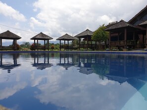 A swimming pool with clear reflections, surrounded by wooden gazebos and a mountainous backdrop. - Degung Hillside (Ciawi)
