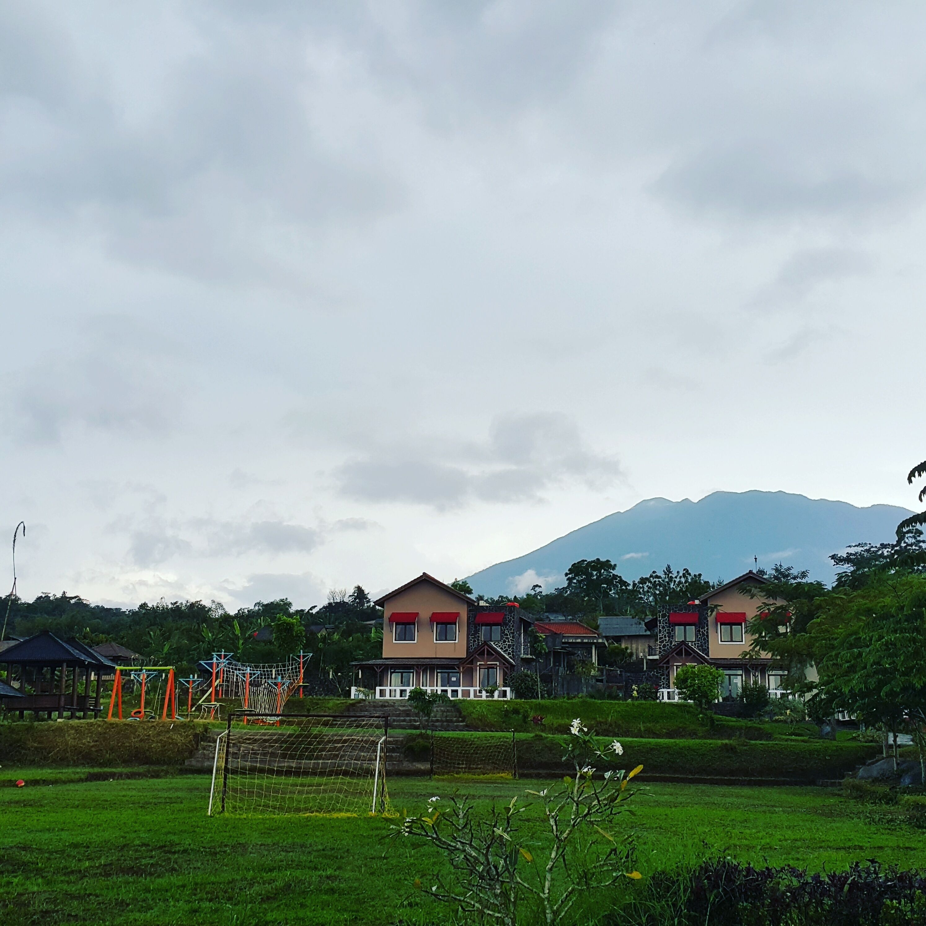 Un barrio residencial con casas, un campo de fútbol y una montaña al fondo.